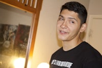 a young man smiling in front of a mirror