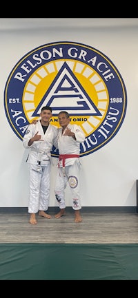 two men posing for a photo in front of a sign for person grace jiu jitsu