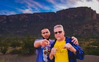 two men pointing at each other in front of a mountain