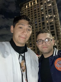 two men posing for a photo in front of a building